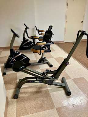 An exercise room with two exercise bikes and another exercise machine.