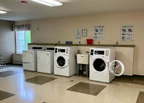 A laundry room with a row of washers and dryers.