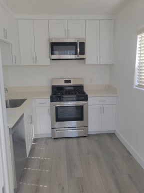 Kitchen with Hardwood Floors, White Cabinets and Stainless Steel Appliances