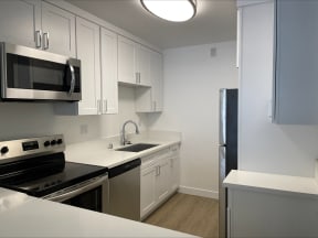 Kitchen with Hardwood Floors, White Cabinets and Stainless Steel Appliances