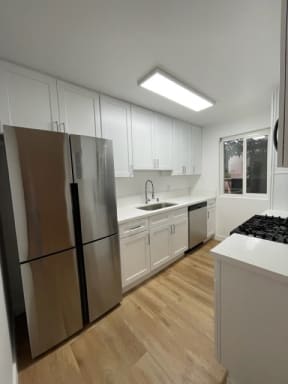 Kitchen with Hardwood Floors, White Cabinets and Stainless Steel Appliances