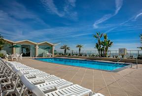 A poolside area with sun loungers and a building in the background.