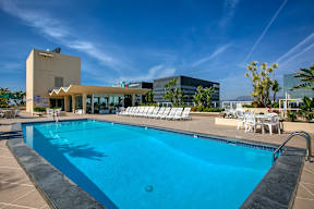 A swimming pool with sun loungers and a building in the background.