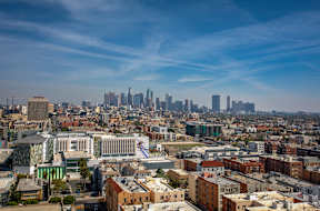 A cityscape with a mix of modern and older buildings under a clear sky.