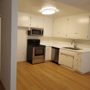 Kitchen with Hardwood Floors, White Cabinets and Stainless Steel Appliances