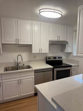 A kitchen with white cabinets and a black stove.