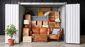 A shipping container is filled with furniture and a plant.