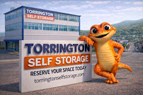 A cartoon alligator stands next to a Torrington Self Storage sign.
