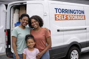 A Torrington Self Storage van with three people standing in front of it.