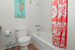 Model bathroom with a white toilet next to a bathtub at Laurel Parc apartments in Shreveport, LA.