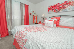 A bed with a white comforter and red pillows in our model apartment at Laurel Parc apartments in Shreveport, LA.