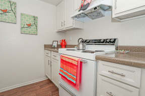 A kitchen with a white stove and white cabinets at Laurel Parc apartments in Shreveport, LA.