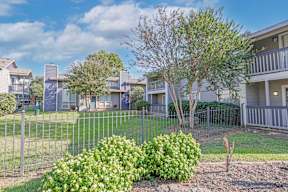 Lush landscaping with apartment buildings in the background at Laurel Parc apartments in Shreveport, LA.