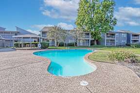Our sparkling swimming pool with apartment buildings in the background at Laurel Parc apartments in Shreveport, LA.