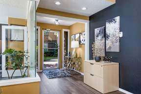 Entrance to leasing office with a wooden cabinet and a plant on a stand. at Stone Canyon apartments in Shreveport, LA.