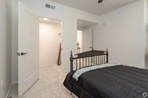 A bedroom with a black bed and a wooden stick leaning against the wall.