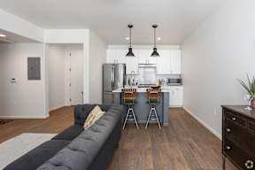 A modern kitchen with a long grey sofa in the middle.