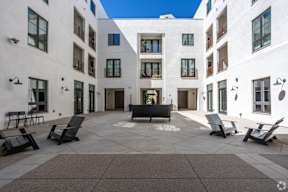 A courtyard with a bench and chairs in front of a white building.