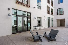 Two black benches are placed on a patio in front of a white building.