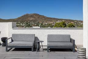 Two grey couches on a patio with a mountain in the background.