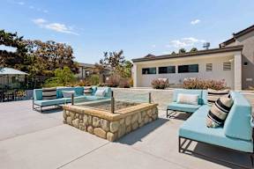 A patio with a stone wall and blue couches.