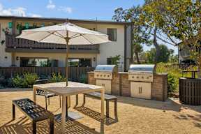 A patio with a table, chairs and an umbrella.