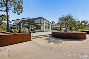 A modern building with a glass entrance and a circular planter in front.