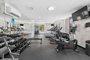 A gym with a variety of equipment including treadmills, stationary bikes, and weight machines.