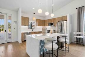A modern kitchen with a white island and bar stools.
