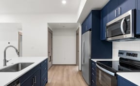 Galley kitchen with stainless steel appliances and blue cabinetry at The Woods at Copper Ranch Apartments, Hailey, ID 83333