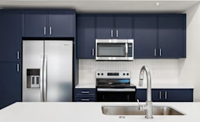 Kitchen with stainless steel appliances and navy cabinets at The Woods at Copper Ranch Apartments, Hailey