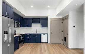 Modern kitchen with navy cabinets and stainless appliances at The Woods at Copper Ranch Apartments, Idaho