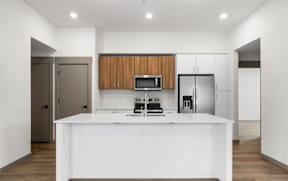 Open concept kitchen with white island and wood cabinets at The Woods at Copper Ranch Apartments, Hailey, Idaho