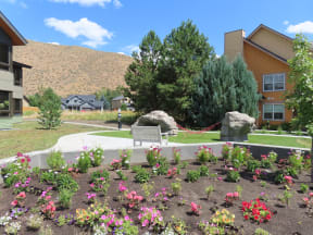 a park bench in front of a garden with flowers  at Lido Apartment Homes @ Hailey, ID, Hailey, ID 83333