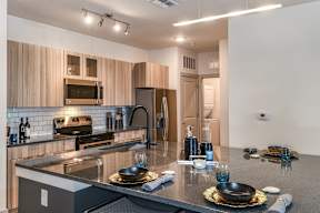 A modern kitchen with a granite countertop and stainless steel appliances. at CODA Apartments , Florida, 32826