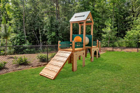a wooden playset with a ramp and a slide in the middle of a grassy area