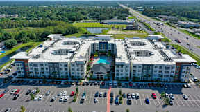 A large white building with a pool in the middle of it. at CODA Apartments , Orlando, FL, 32826