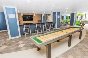 a game room with a shuffleboard table and a bar
