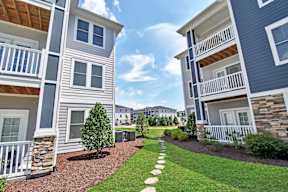 View of a small garden with a pathway and a small tree in between two buildings at HAVEN POINTE AT CAROLINA FOREST APARTMENTS, Myrtle Beach, SC