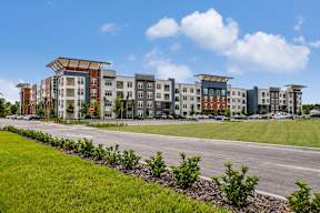 A row of modern apartment buildings with green grass in front. at CODA Apartments , Orlando, FL, 32826