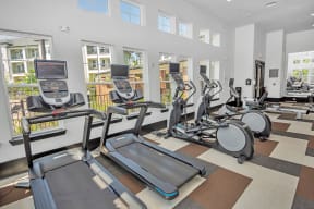 a room filled with lots of cardio equipment and a large window