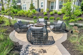 a circular patio with a fire pit and wicker furniture