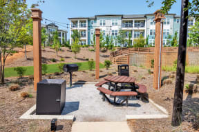 a picnic table with a barbecue grill and picnic table in front of an apartment building