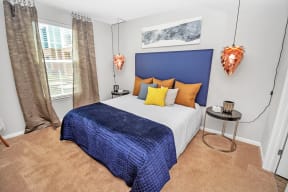 a bedroom with a bed with a blue headboard and orange and yellow pillows