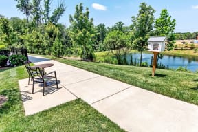 a patio with a table and chairs and a bird house next to a river