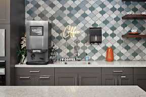 a kitchen with a coffee maker on a counter and a tile wall