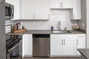 a white kitchen with stainless steel appliances and white cabinets