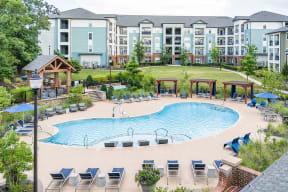 an outdoor pool with chairs around it and an apartment building