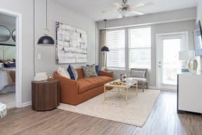 a living room with a brown couch and a ceiling fan