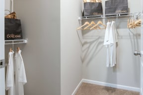 a walk in closet with white clothes and bags on the rack and a closet door